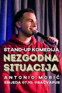 Plakat stand-upa Nezgodna situacija s Antonijem Morićem u crvenoj majici s kapuljačom, koji drži mikrofon ispred zastora.