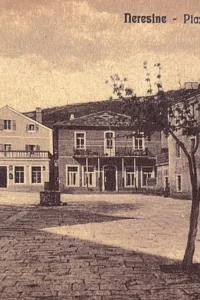 Stara razglednica u sepija tonovima prikazuje popločeni trg u Nerezinama, ljude, okolne kuće i stabla, uz natpis Neresine – Piazza Vittorio Emanuele III.